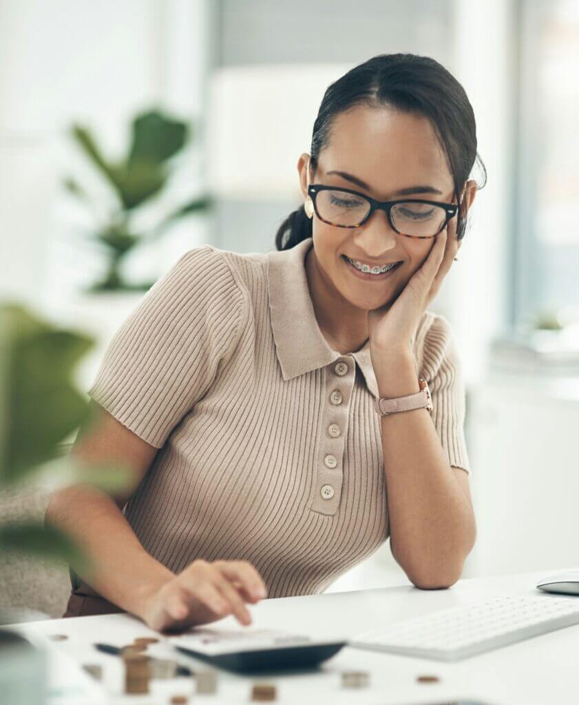 Shot of a young businesswoman calculating finances in an office