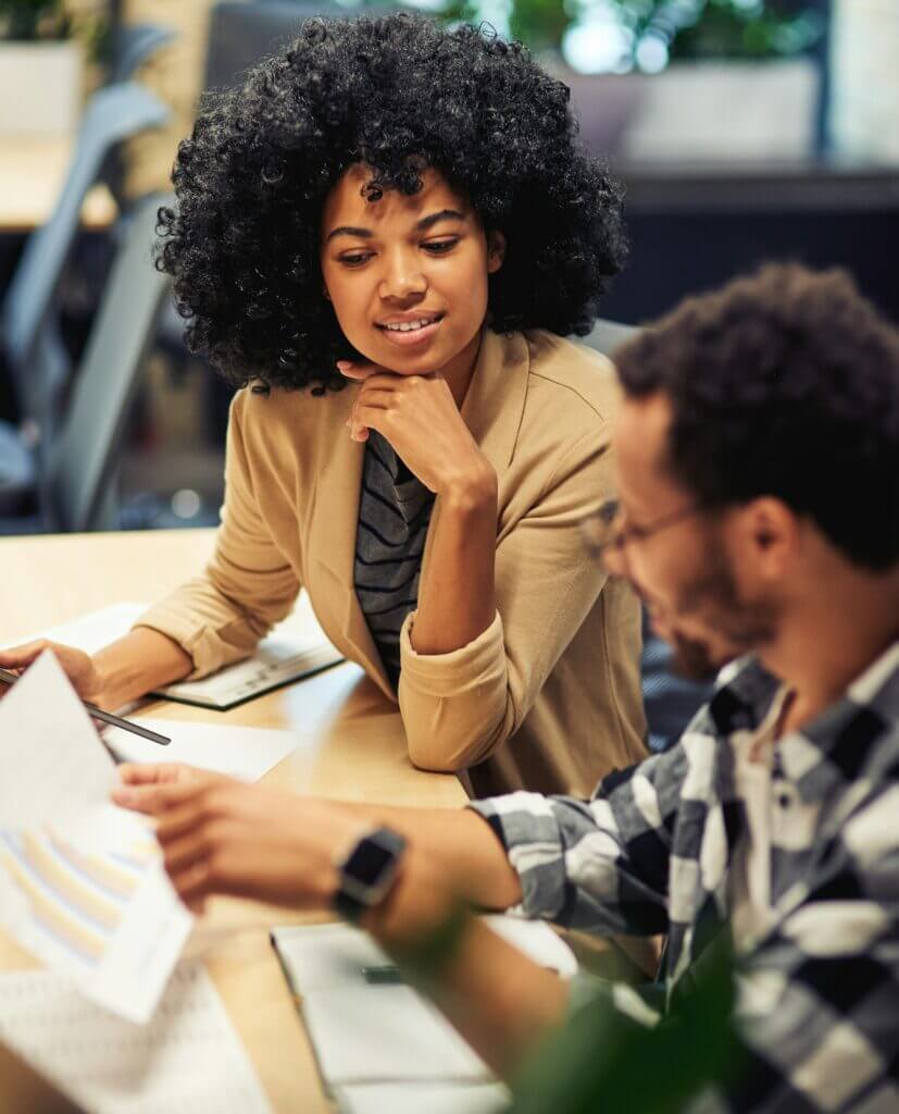 Two young diverse coworkers analyzing sales report while working together in the office