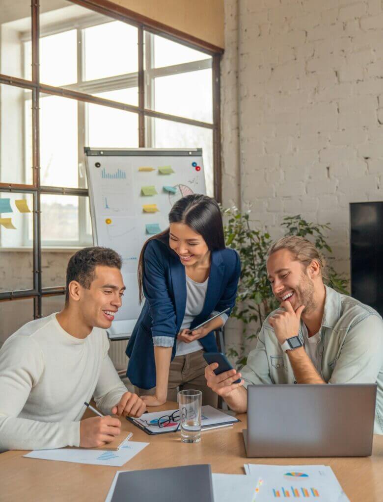 Vertical shot of multiracial business people with laptop and smartphone having meeting in office.